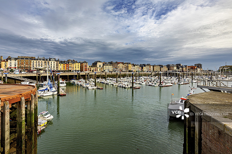 诺曼底法国迪耶普的港口，许多船只和历史建筑在戏剧性的天空下。图片素材