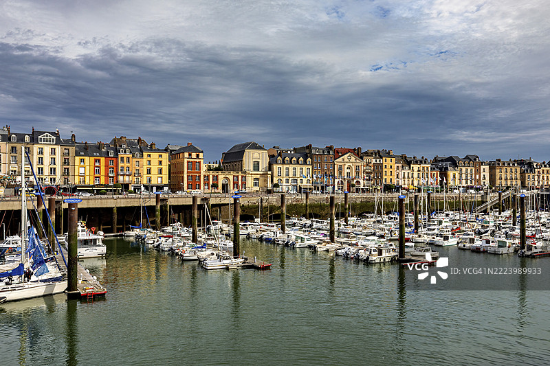 历史建筑沿着满是船只的港口而立，天空多云，这是法国诺曼底的迪耶普港。图片素材