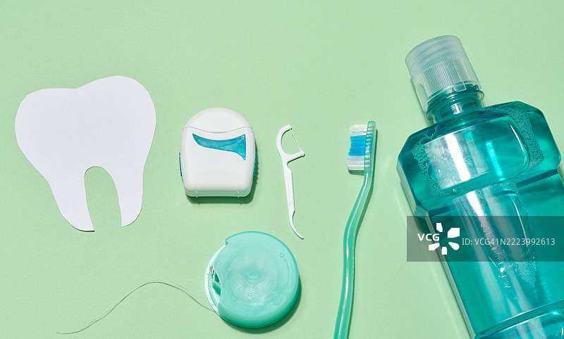 各种牙齿卫生产品，包括纸质牙齿剪影、牙线盒、牙线夹、牙刷和漱口水，背景为浅绿色，乌克兰图片素材