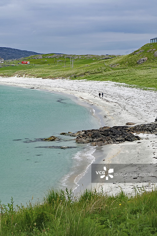 海岸风景，草地、平静的海面和在白色沙滩上散步的人们，埃里克赛，巴拉岛，苏格兰，英国，欧洲图片素材