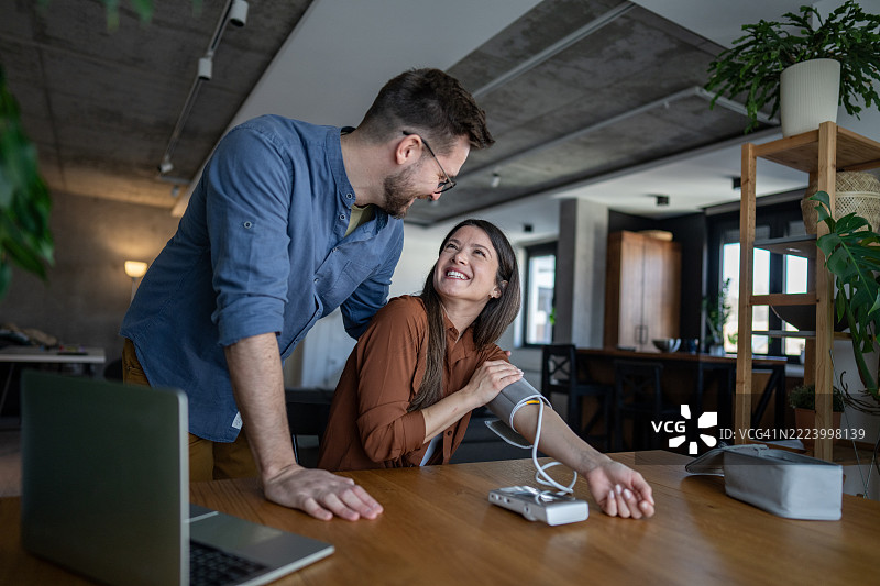 年轻夫妇在家用数字设备测量血压图片素材
