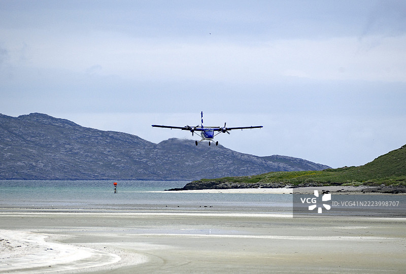一架飞机在海滩的跑道上降落,背景是山脉,气氛宁静,外赫布里底群岛,巴拉岛,苏格兰,英国,欧洲图片素材