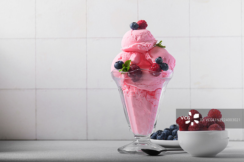 粉色冰淇淋配新鲜浆果和薄荷，盛在玻璃碗中图片素材