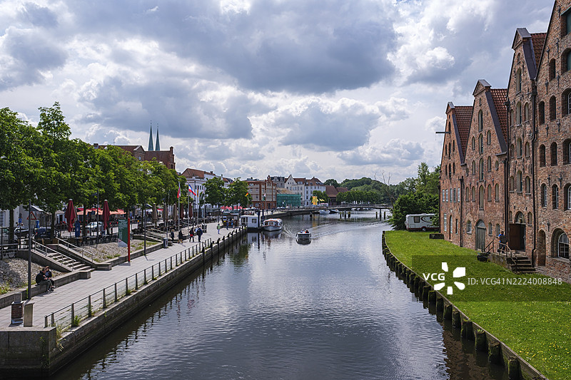城市景观，水道与历史砖砌建筑相伴，绿地和云彩环绕，德国吕贝克，石勒苏益格-荷尔斯泰因，欧洲图片素材
