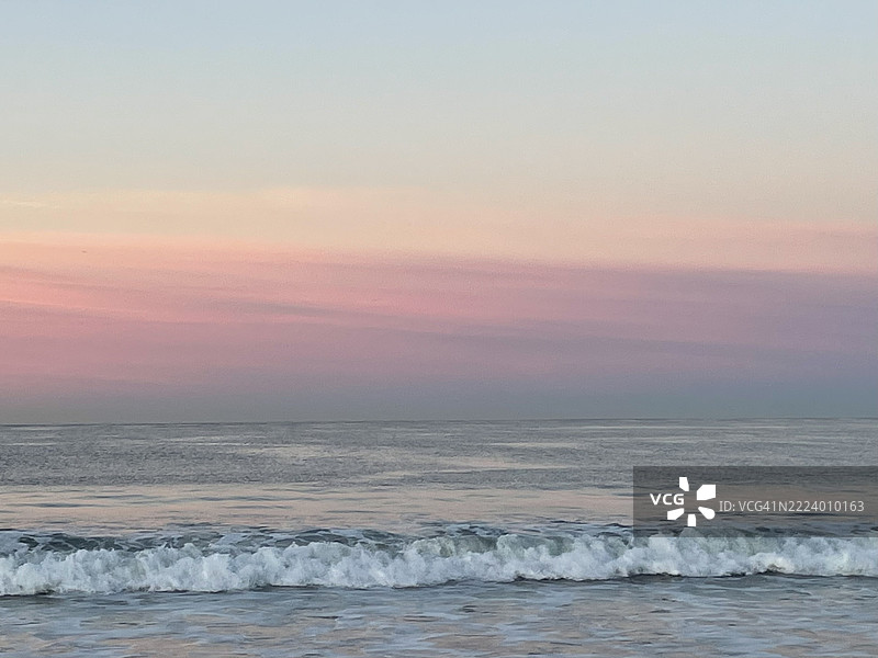 洛杉矶，加利福尼亚州，美国，海洋中泡沫波浪下的微妙粉色、黄色、橙色和灰色天空图片素材