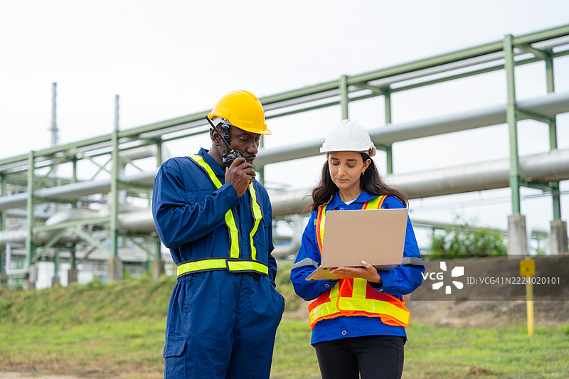 工程师在工业石油炼油厂附近监测环境条件图片素材