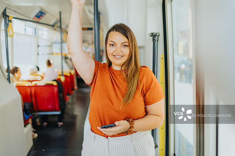 微笑的女性在乘坐火车通勤时查看手机信息图片素材