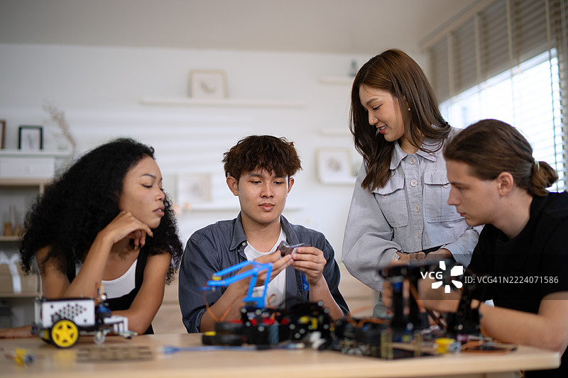 一群年轻的大学生正在集思广益，讨论如何制作机器人。图片素材