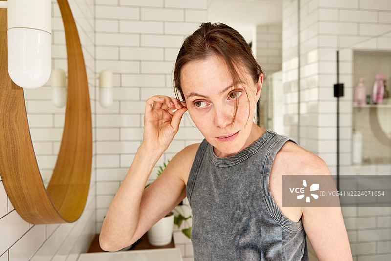 女人在现代浴室里用手指清洁耳朵图片素材