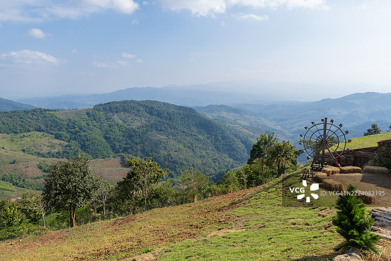 木制水轮，山丘上有干草方块，蓝天背景下的水轮。图片素材