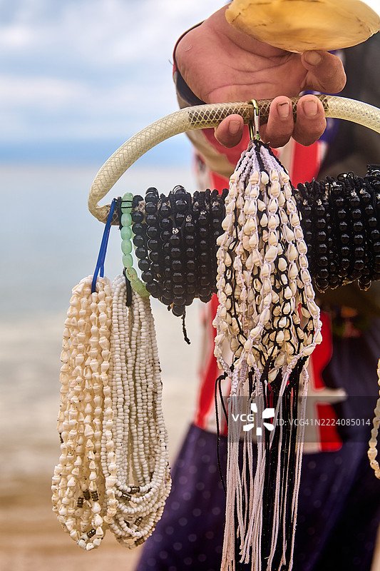 一位纪念品商贩手持一束珠子饰品。图片素材