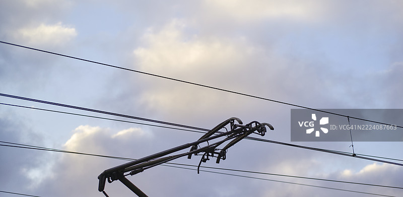 云层下的火车受电弓与高架电线交错在一起图片素材