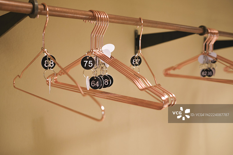在明亮的房间里，铜衣架上挂着带有编号钥匙链的物品图片素材