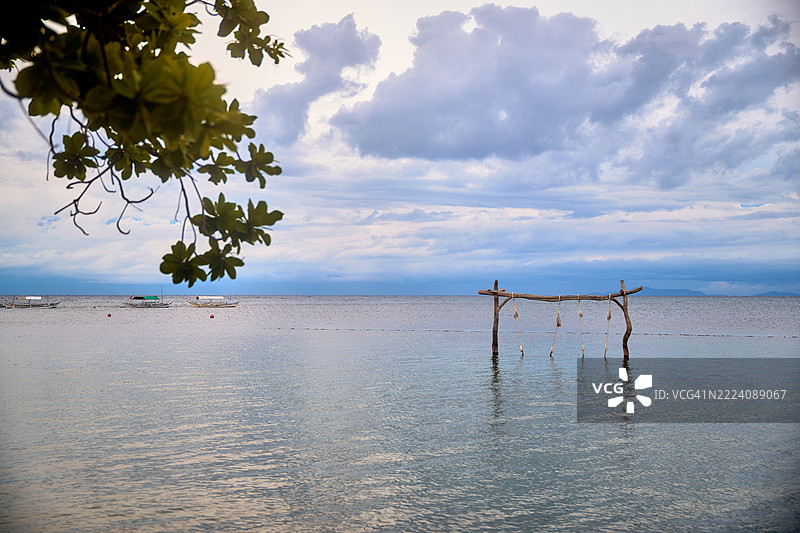 一个木秋千部分浸在平静的水中。图片素材