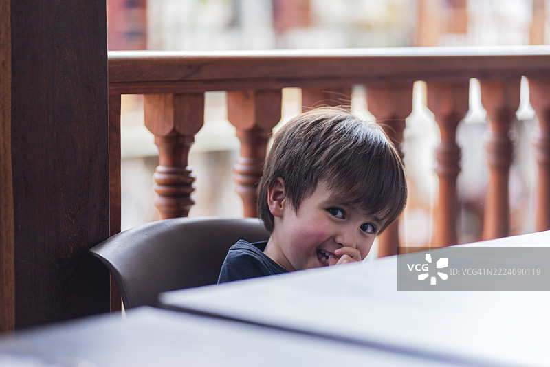 男孩在家阳台上眺望，观看游客们走过博亚卡的拉基拉镇。图片素材