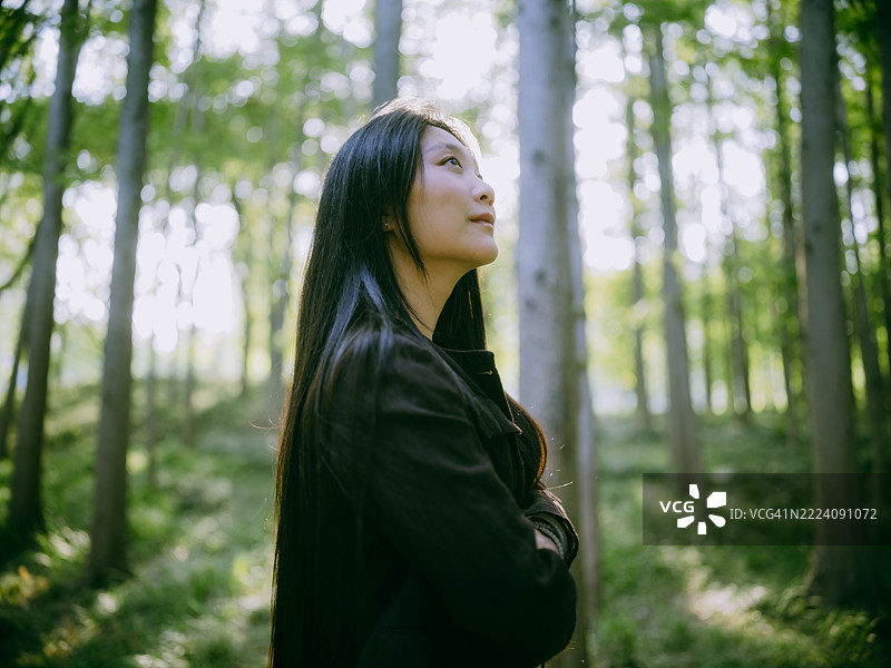 自信的亚洲女商人在森林中双臂交叉，呼吸新鲜空气，与自然连接。图片素材
