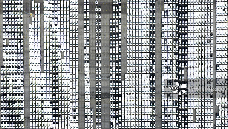 工厂停车场的新车俯视图。上方视角的汽车排成一排。汽车工业。物流业务。在仓库进口或出口新车。港口码头的大型停车场。图片素材