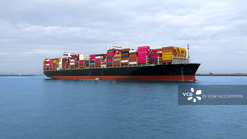 从上方看满载的集装箱船驶向港口，国际集装箱船在海港装卸货物，货运运输，航运，物流，进出口，运输。全球图片素材
