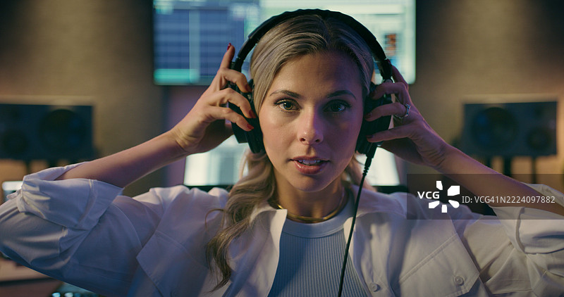 夜间录音室中的女性音响工程师，佩戴耳机进行人像拍摄和制作。创意、媒体和音乐，DJ在工作中进行混音或试听测试，作为音频制作人。图片素材