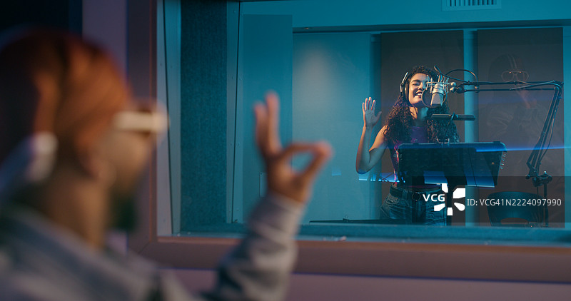 录音室，OK手势和与制作人的女性正在为唱片、曲目和音频录制歌曲。创意、音乐行业和技术人员，带有艺术家的表情符号，表现出良好的表演、声音和排练。图片素材