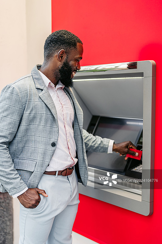 中年非裔美国商人在迈阿密市中心的ATM机上使用信用卡取款图片素材