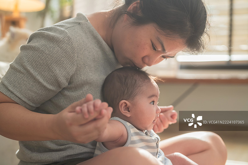 特写镜头中，母亲温柔地握着婴儿的小手，象征着爱与关怀，珍贵的家庭纽带，柔和温暖的色调和细腻的细节，营造出情感丰富的母性与育儿形象，代表着家庭价值观和亲密联系。图片素材