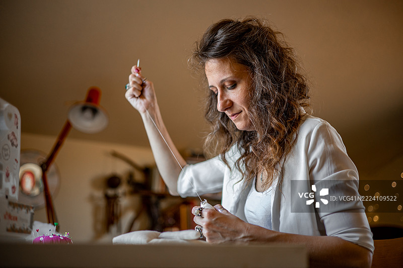 创意女性工匠在温馨宜人的手工工作室设计和缝制手工布艺娃娃——为客户订单准备独特作品图片素材