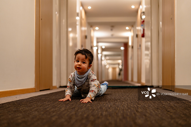 年轻男孩在明亮的酒店走廊里爬行图片素材
