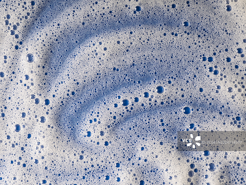 蓝色表面覆盖着泡沫和肥皂泡。图片素材