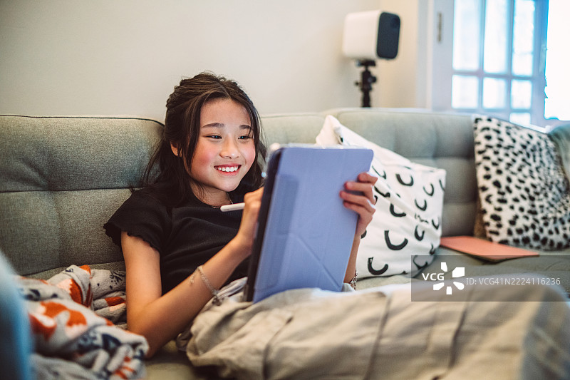 青少年女孩在家放松，使用手写笔在平板上绘画图片素材