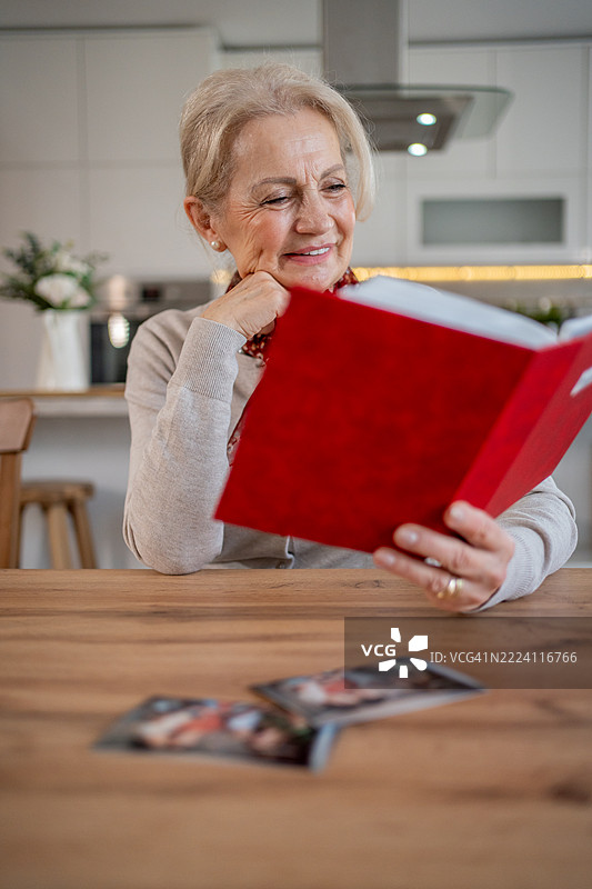 快乐的老年女性在家中翻阅相册并微笑图片素材