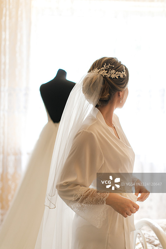 年轻女子穿着丝绸浴袍，正在为婚礼做准备。新娘的早晨。图片素材