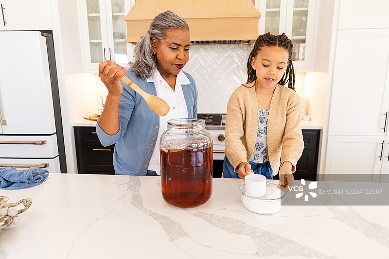 祖母和孙女在厨房一起制作甜茶图片素材