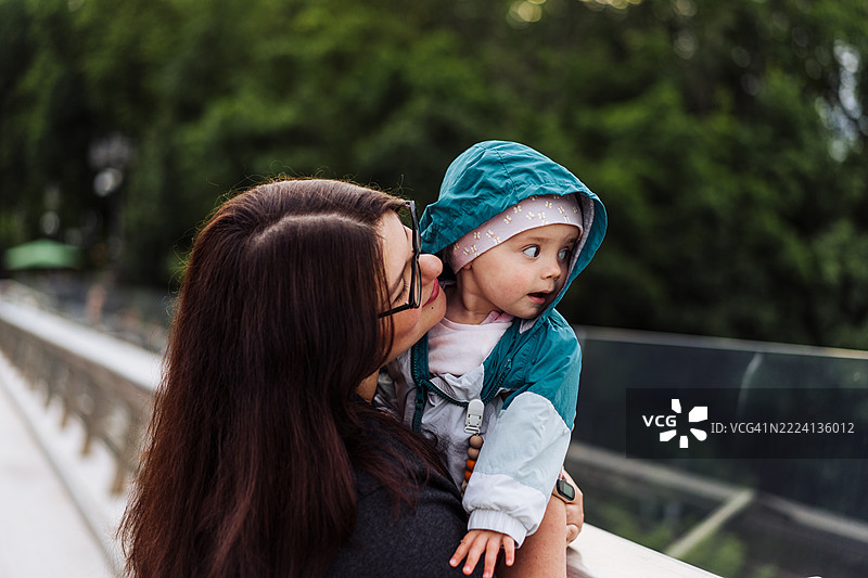 母亲在户外拥抱微笑的孩子的快乐时刻图片素材