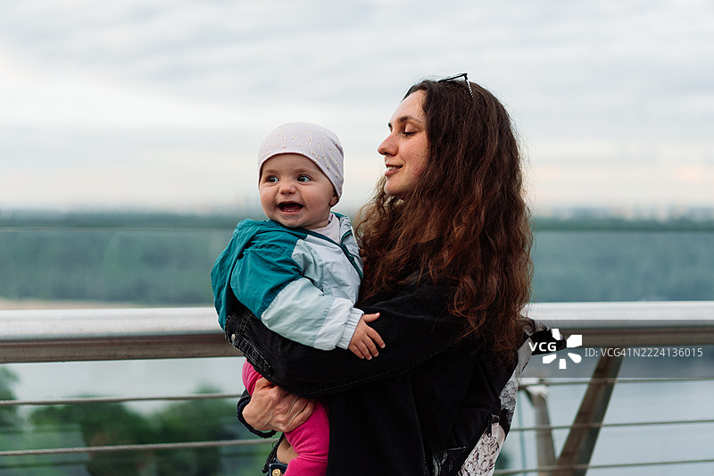 母亲在户外拥抱微笑的孩子的快乐时刻图片素材