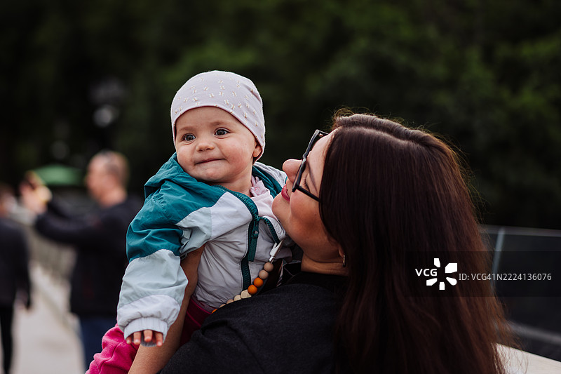 母亲在户外拥抱微笑的孩子的快乐时刻图片素材