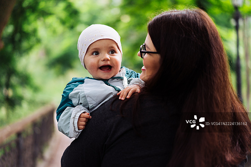 母亲在森林背景中抱着微笑的宝宝图片素材