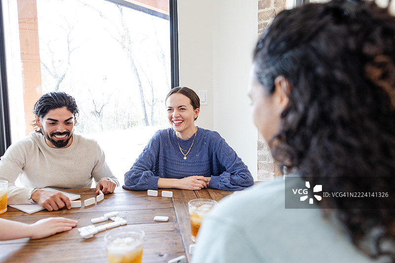 三位朋友在室内享受轻松的多米诺骨牌游戏图片素材