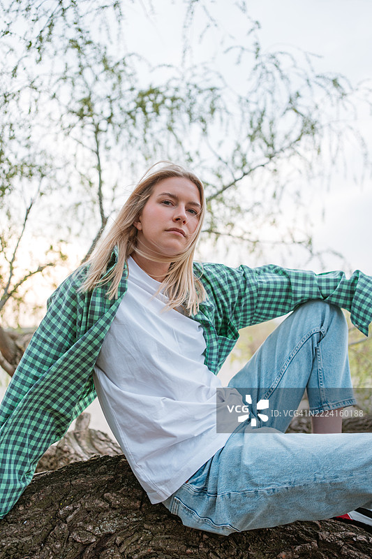 自然休息。女人在户外舒适地坐在坚固的倒下树干上。图片素材