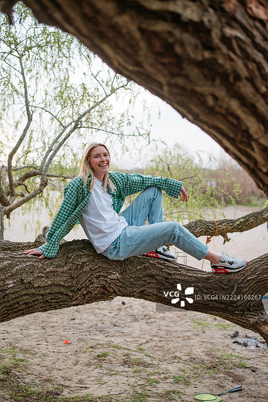 自然放松。女人坐在沙滩上的倒下树木上，享受新鲜空气。图片素材