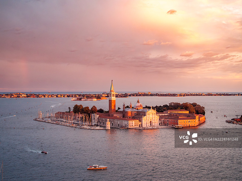 日落时分的圣乔治大教堂（或大教堂）及其岛屿的鸟瞰图，这是一座著名的本笃会文艺复兴建筑，前方是满载摩托艇的威尼斯泻湖，联合国教科文组织世界遗产 - 威尼斯 - 威尼托 - 意大利。图片素材