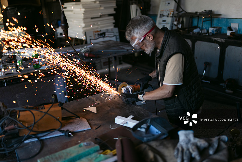 金属工人在车间使用角磨机产生火花图片素材