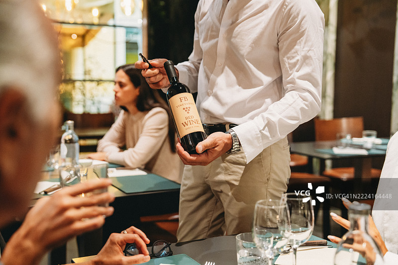 服务员在餐厅向顾客展示红酒瓶图片素材