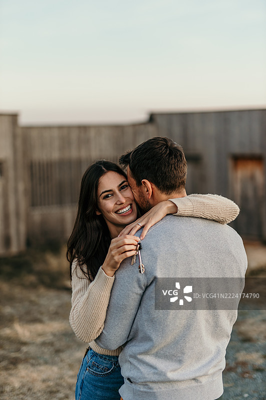 幸福的情侣拥抱着，手中握着新房钥匙图片素材