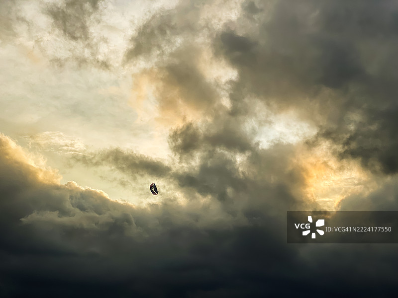 风筝的剪影映衬在戏剧性的天空云朵背景下图片素材