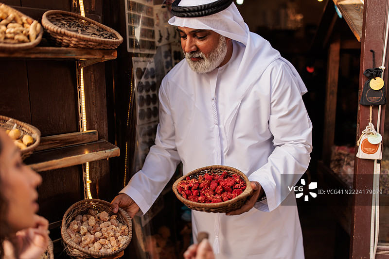 阿拉伯店主在旧迪拜市场向顾客展示香料图片素材