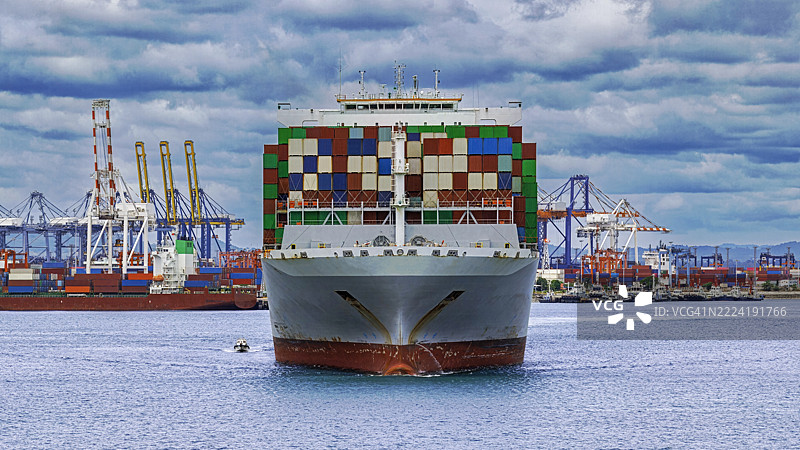 满载集装箱的货船从空中视角接近港口。图片素材