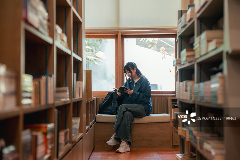 Gen Z woman explores a bookstore aisle, picking out her next read, embracing aesthetic reading culture and mindful living图片素材