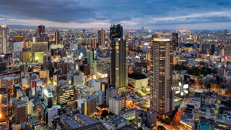 日本大阪黄昏时分在多云天空下闪耀的城市天际线图片素材