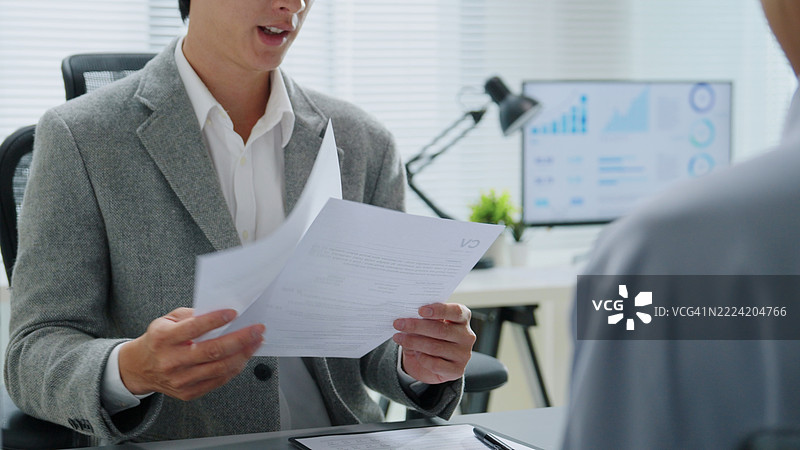 人力资源经理在办公室面试求职者，女性招聘人员正在阅读简历，准备招聘相关的文件或简历以评估技能或工作机会。图片素材